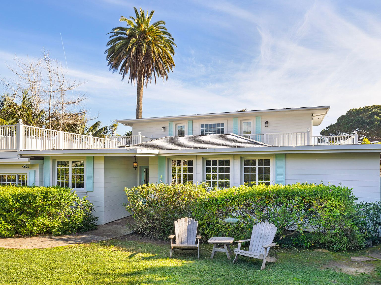 Front elevation of the cottage framed by a mature palm