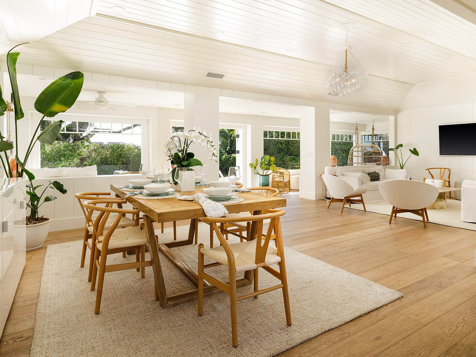 Open plan great room with wishbone chairs, farmhouse table, and white vaulted ceiling